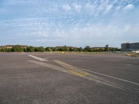 an empty runway with no people in it but a few buildings around the plane line