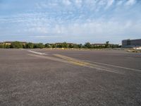 an empty runway with no people in it but a few buildings around the plane line