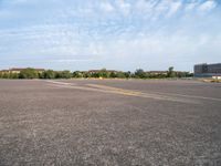 an empty runway with no people in it but a few buildings around the plane line