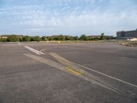 an empty runway with no people in it but a few buildings around the plane line