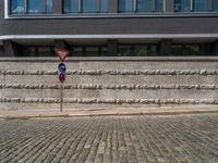 a cobblestone street next to two buildings with street signs on them, on a partly cloudy day