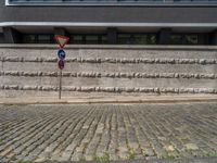 a cobblestone street next to two buildings with street signs on them, on a partly cloudy day