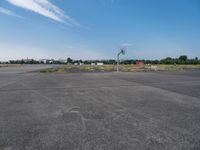 an empty parking lot is pictured from inside the picture while in focus there are trees and a red building in the background