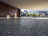 an empty street in the middle of some tall buildings, with concrete pillars, and one door open