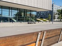 the sidewalk beside the building has a small brick bench next to it with a glass facade