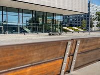 the sidewalk beside the building has a small brick bench next to it with a glass facade