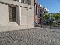 two people walking down an empty city street in an alley area with tall buildings in the background