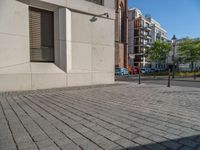 two people walking down an empty city street in an alley area with tall buildings in the background