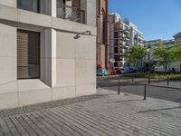 two people walking down an empty city street in an alley area with tall buildings in the background