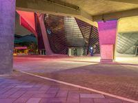 the large square in front of a building that has an open entry way on one side and a purple entrance on the other