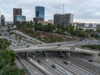 a highway with many cars traveling under an overpass, surrounded by trees and buildings