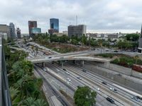 a highway with many cars traveling under an overpass, surrounded by trees and buildings