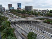 a highway with many cars traveling under an overpass, surrounded by trees and buildings