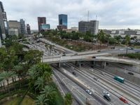 a highway with many cars traveling under an overpass, surrounded by trees and buildings