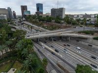 a highway with many cars traveling under an overpass, surrounded by trees and buildings