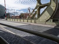 some old train tracks near a bridge and buildings and people walking by some cars and a train