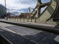 some old train tracks near a bridge and buildings and people walking by some cars and a train