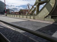 some old train tracks near a bridge and buildings and people walking by some cars and a train