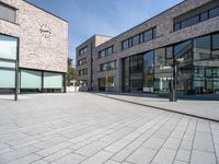 an open brick plaza in a city with modern architecture, and many windows, on a sunny day