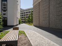 a wooden bench sitting in the middle of a courtyard area next to buildings in the background