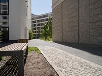 a wooden bench sitting in the middle of a courtyard area next to buildings in the background