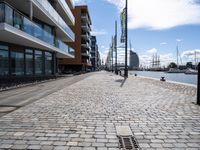 a large empty walkway between two buildings and water street lights on the pavement in front of them