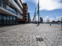 a large empty walkway between two buildings and water street lights on the pavement in front of them