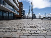 a large empty walkway between two buildings and water street lights on the pavement in front of them