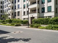 a building in the street with lots of shrubs around it and some trees on either side