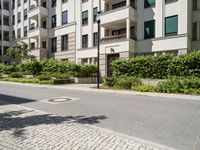 a building in the street with lots of shrubs around it and some trees on either side