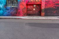 a fire hydrant on the side of a road with red graffiti painted all over it