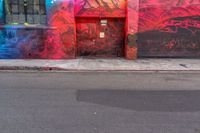 a fire hydrant on the side of a road with red graffiti painted all over it