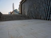 the view of a building from across the concrete walkway outside the building with no roof