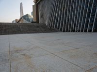 the view of a building from across the concrete walkway outside the building with no roof