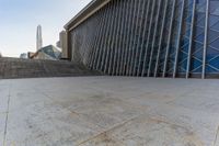 the view of a building from across the concrete walkway outside the building with no roof