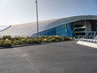 a view of a futuristic building with many windows, from across the street from the entrance to it