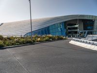 a view of a futuristic building with many windows, from across the street from the entrance to it