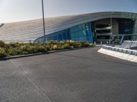 a view of a futuristic building with many windows, from across the street from the entrance to it