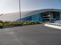 a view of a futuristic building with many windows, from across the street from the entrance to it