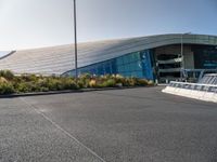 a view of a futuristic building with many windows, from across the street from the entrance to it