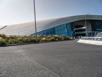 a view of a futuristic building with many windows, from across the street from the entrance to it