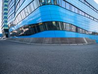 a man holding a frisbee standing on a road near a building that looks very futuristic