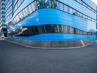 a man holding a frisbee standing on a road near a building that looks very futuristic