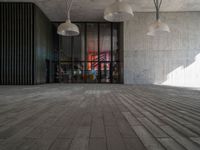 a light hanging from the ceiling in an office building with wood flooring and large windows