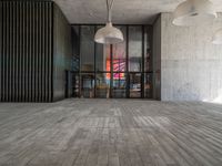 a light hanging from the ceiling in an office building with wood flooring and large windows