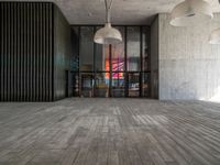 a light hanging from the ceiling in an office building with wood flooring and large windows