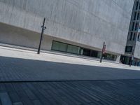 an empty street in front of a modern building in europe, the street is lined with brick paving