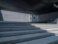 a woman wearing a hat rides a skateboard in front of some stairs at an architectural building