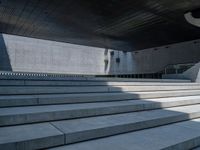 a woman wearing a hat rides a skateboard in front of some stairs at an architectural building