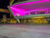 a purple lit building is on the street with a man walking across the sidewalk in front